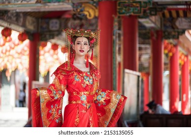 portrait of a woman. person in traditional costume. woman in traditional costume. Beautiful young woman in a bright red dress and a crown of Chinese Queen posing against the ancient door.  - Shutterstock ID 2153135055