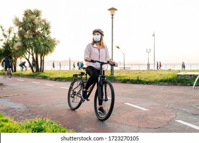 Portrait of a woman with protective safety mask on her face riding a bike on a bike path in the city on a sunny day. - Powered by Shutterstock