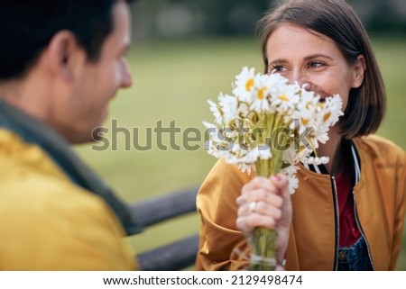 Portrait of a woman receiving a bouquet of flowers from a man; Inlove couple concept