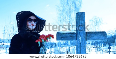 Portrait of a woman with red flowers near a wooden cross
