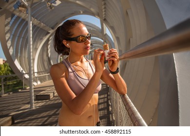 Portrait Of A Woman Runner Eating An Energy Bar, Outdoors On A Sunny Day
