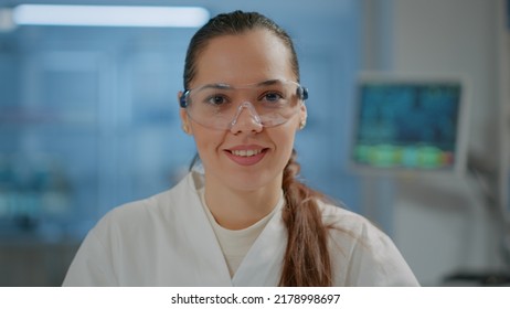 Portrait Of Woman Scientist With Goggles Smiling In Laboratory, Getting Ready To Work On Science Experiment And Development. Microbiology Researcher Wearing Safety Glasses In Lab. Close Up