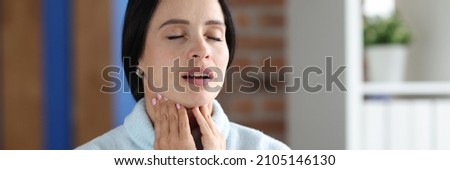 Portrait of woman sitting with closed eyes and sore throat on sofa. Painful symptoms in throat concep Foto stock © 