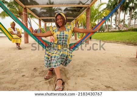 Portrait of a Garífuna woman sitting in hammocks enjoying the sun and sea breeze. Beautiful African American woman enjoying being with her girlfriends on vacation.