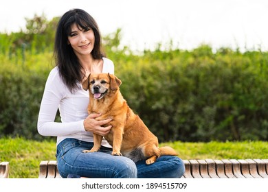 Portrait of a woman sitting on a bench in the park with her old dog	