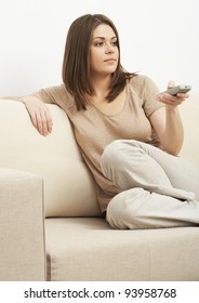 Portrait of woman sitting on sofa and holding  remote control panel TV