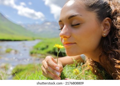 Portrait of a woman smelling a flower in the mountain in a riverside