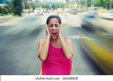 Portrait of woman standing still in the middle of a street with cars passing by fast, screaming stressed and frustrated  - Powered by Shutterstock