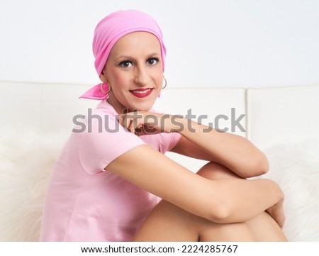 portrait of a woman suffering from breast cancer with a pink scarf sitting and resting her chin on her hand