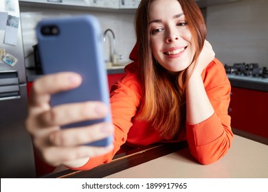 Portrait of woman taking selfie photo in modern kitchen. Colorful interior