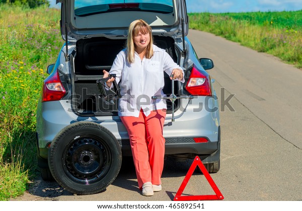 portrait of a woman with tools for changing a wheel\
near the car