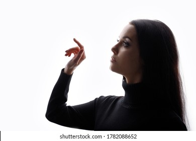 Portrait Of Woman Touching The Visual Screen With Her Finger. White Background. Young Female In Profile Touches Somethingin The Air. Free Space For Text.