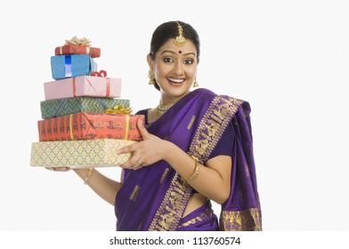 Portrait of a woman in traditional Assamese dress holding gifts and smiling