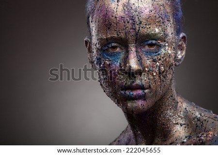 Portrait of woman with unusual paint make-up and face art on dark background