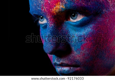 Portrait of woman with unusual paint make-up on black background