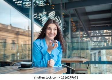 Portrait Of A Woman Using The Voice Recognition Of The Phone Sitting In A Trendy Cosy Coffee Shop Cafe In Manhattan New York Or At The Balcony Of Her Home