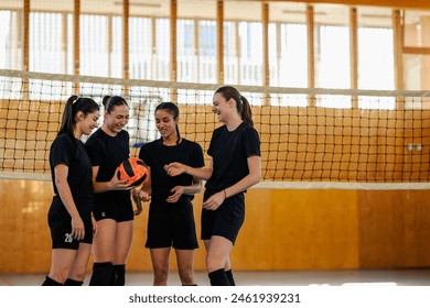 Portrait of a woman volleyball players standing together at the net and holding the ball in an indoor volleyball court. Diverse female volleyball players standing on court and training. Copy space. - Powered by Shutterstock