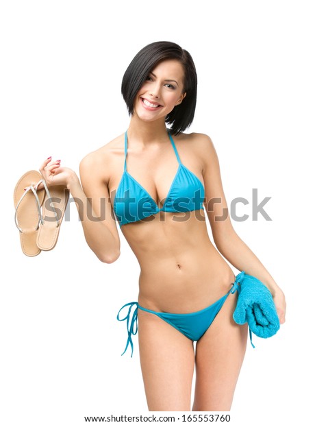 Portrait of woman wearing bikini and keeping towel and thongs, isolated on white. Concept of summer holidays and traveling