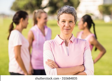 Portrait of woman wearing pink for breast cancer in front of friends in parkland