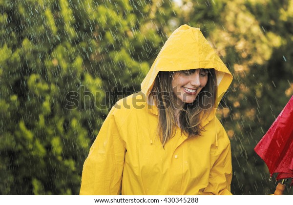 雨の中で黄色いレインコートを着た女性のポートレート の写真素材 今すぐ編集