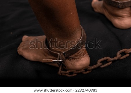 Portrait of woman's legs chained with old rusty metal chain and padlock. Slave trade prevention concept.
