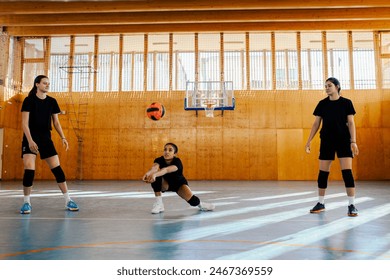 Portrait of a women volleyball players showcasing their skills in an indoor volleyball match. Diverse female athlete receiving a ball with a bump while her teammates standing next to her. Copy space. - Powered by Shutterstock