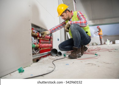 Portrait Of A Worker, Constructing And Checking Development Of A Small Business Hall. Reliable Civil Engineer Working On A Construction Site, Foreman At Work, Another Man In The Background