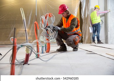 Porträt eines Arbeitnehmers, Bau und Prüfung der Entwicklung eines kleinen Betriebshauses. Zuverlässiger Bauingenieur, der auf einer Baustelle arbeitet, Arbeiter, ein anderer Mann im Hintergrund