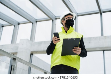 Portrait Of Worker With Face Mask At The Airport, Holding Smartphone.