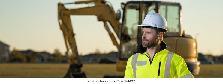 Portrait of worker man small business owner. Construction worker with hardhat helmet on construction site. Construction engineer worker in builder uniform with excavation truck digging. Worker - Powered by Shutterstock