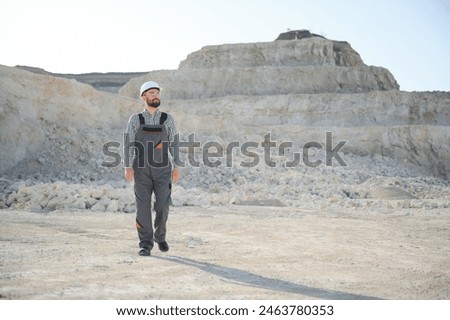 Portrait of a worker standing on the background of a stone quarry.