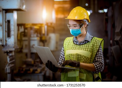 Portrait worker under inspection and checking production process on laptop factory station by wearing safety mask to protect for pollution and virus in factory. - Shutterstock ID 1731253570