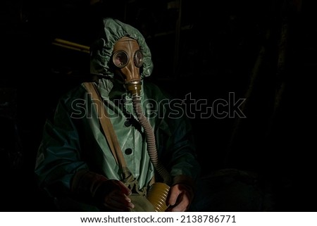 Portrait of worker wearing green anti radiation costume and gas mask against black background