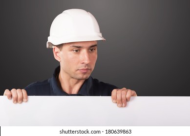 Portrait of a workman in dark blue coveralls and white hardhat holding a blank copy space - Powered by Shutterstock