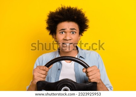 Portrait of worried nervous guy wear jeans jacket hold steering wheel biting lips get in accident isolated on yellow color background