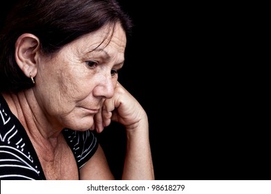Portrait of a worried old woman with a sad expression isolated on black