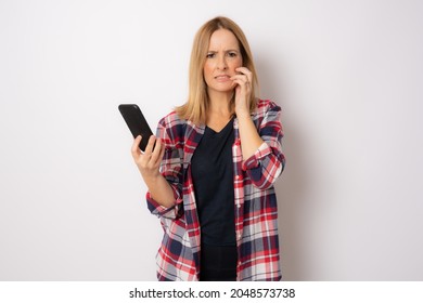 Portrait Of A Worried Young Casual Woman Using Mobile Phone Isolated Over White Background