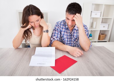 Portrait Of A Worried Young Couple Looking At Paper