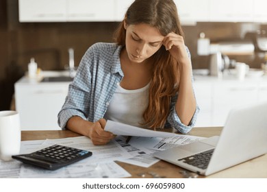 Portrait Of Worried Young Single Mother Feeling Stressed While Working Through Finances In Kitchen Late At Night, Thinking How To Pay Off Debts For Rent And Domestic Bills. Financial Problems Concept