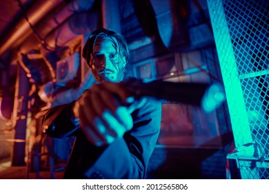 Portrait Of A Wounded Action Hero Man Aiming A Gun In The Light Of The Night City. 