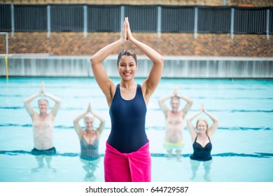 Portrait of yoga instructor assisting senior swimmers at poolside - Powered by Shutterstock
