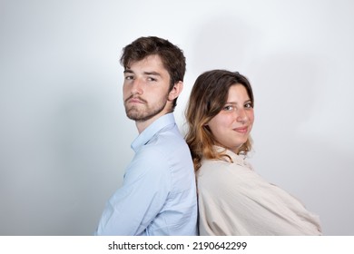 Portrait Of Young 25 Year Old Couple Back To Back Smiling And Looking At Camera. Isolated On Gray Background
