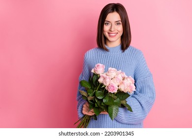 Portrait of young adorable cute smiling woman holding hand roses birthday present isolated on pink color background