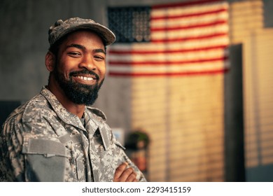 A portrait of a young adult African American army officer inside with the American flag in the background, copy space and looking at camera. - Powered by Shutterstock