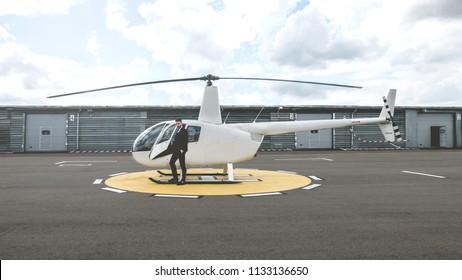 Portrait Of Young Adult Businessman Executive Standing Near A Private Charter Helicopter On A Helipad