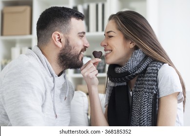 Portrait of young adult caucasian eating a heart chocolate cookie. Valentines couple sharing cookie,shallow depth of field