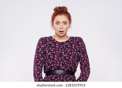 Portrait of young adult ginger woman wearing dress looking at camera with mouth open in amazement, expressing shock, astonishment. Indoor studio shot isolated on gray background. - Shutterstock ID 2281019953