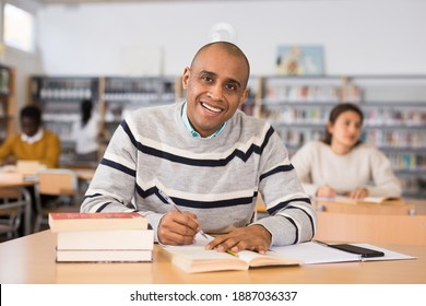 Portrait of young adult man studying in at public library