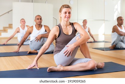 Portrait of young adult sporty woman practicing yoga with group at fitness center