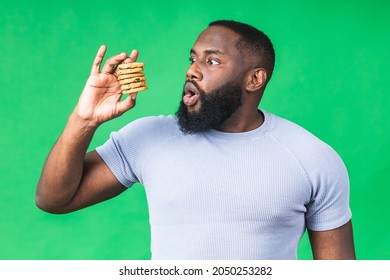 Portrait of young african american black man holding chocolate cookie biscuit isolated on green background.